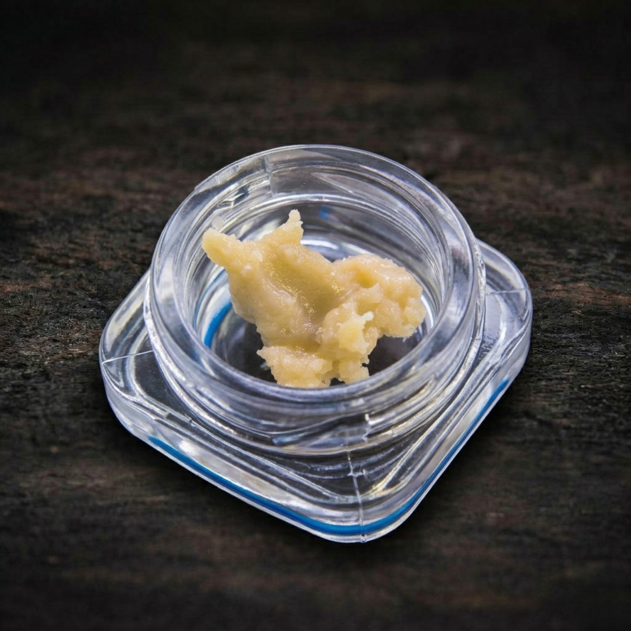 Clump of beige-colored rosin on a dark textured surface