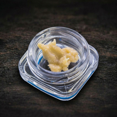 Clump of beige-colored rosin on a dark textured surface